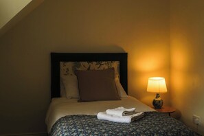 A hotel room with a bed, a nightstand with a lamp, and a window. - Belmont House (Cappoquin)