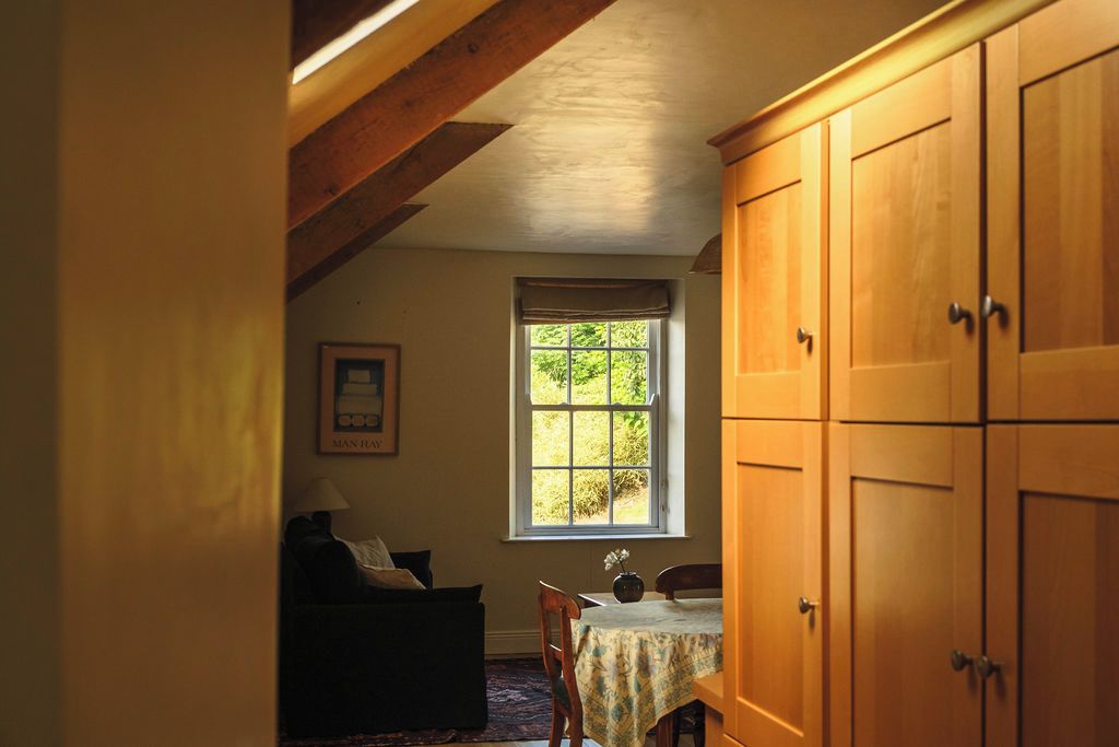 Une pièce comprenant une table à manger, une fenêtre donnant sur un espace verdoyant et des meubles de rangement en bois.