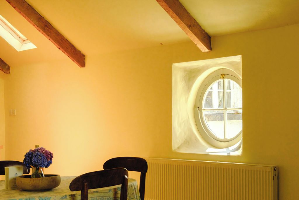 Una habitación con una mesa, sillas, una ventana y un radiador.