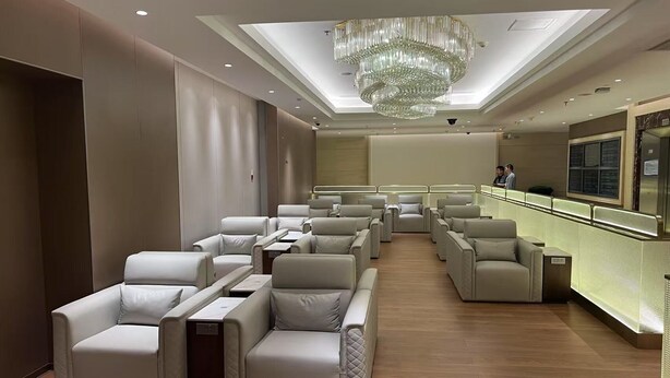 A modern lounge with leather chairs, a central chandelier, and a reception desk.