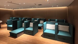 A row of teal cushioned seating areas with wooden flooring and recessed ceiling lighting.