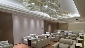A modern lounge with plush seating, a large chandelier, and a wooden floor.