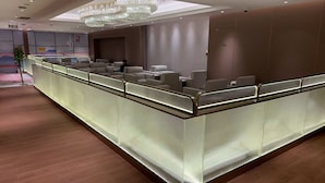 A modern reception area with a long counter, seating, and a chandelier.