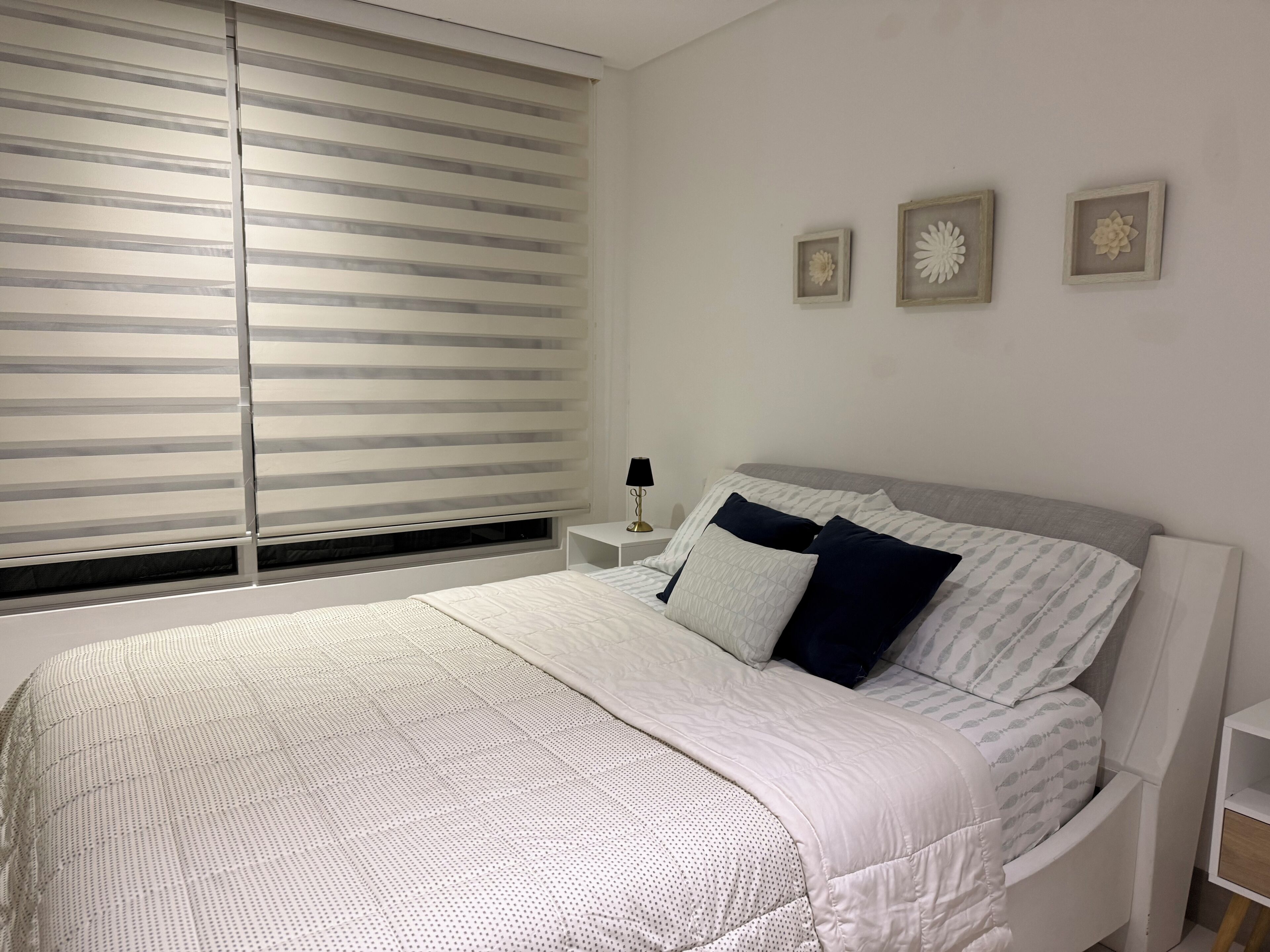 A neatly arranged bedroom with a bed, bedside tables, and decorative wall art.