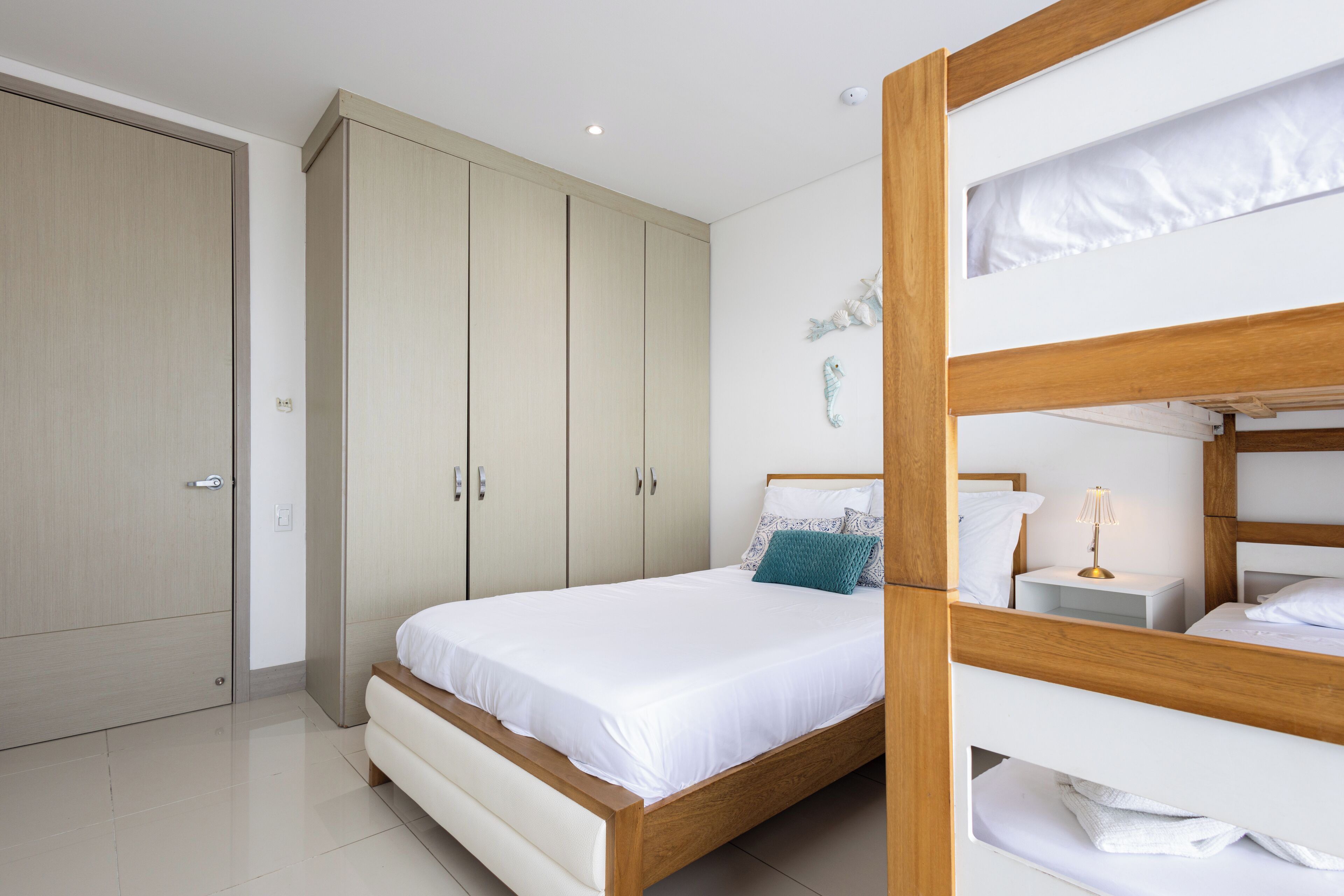 A bedroom with a wooden bed, a white bedside table, and a wardrobe.