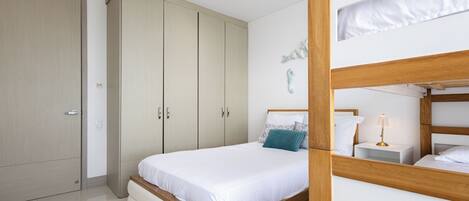 A bedroom with a wooden bed, a white bedside table, and a wardrobe.
