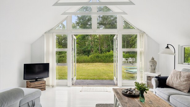 Una sala de estar moderna con un ventanal grande, un televisor de pantalla plana, un sofá, una mesa de centro y una escultura de piedra.