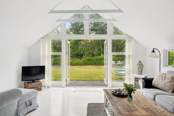 Ein modernes Wohnzimmer mit großem Fenster, Flachbildfernseher, Sofa, Couchtisch und einer Steinskulptur.