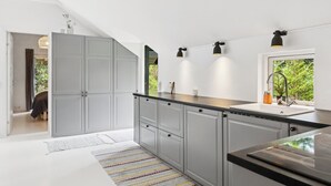 Una cocina moderna con armarios grises, encimera negra y ventana con vista a zonas verdes.