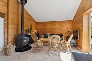 Ein gemütliches Blockhaus mit Kamin, Korbmöbeln und einem Fernseher.