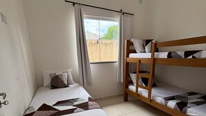 A room with a single bed, a bunk bed, a window with curtains, and a tiled floor. - House in Matinhos with free Wi-Fi and accepts your pet. (Matinhos)