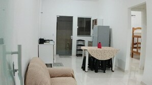 A living room with a sofa, a table with a lace tablecloth, a refrigerator, and a chair. - House in Matinhos with free Wi-Fi and accepts your pet. (Matinhos)