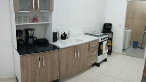 A modern kitchen with a black countertop, wooden cabinets, a white sink, and a stove. - House in Matinhos with free Wi-Fi and accepts your pet. (Matinhos)