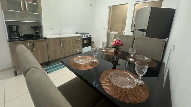 A compact kitchen with a dining table set for four, equipped with a coffee maker, stove, and refrigerator. - House in Matinhos with free Wi-Fi and accepts your pet. (Matinhos)