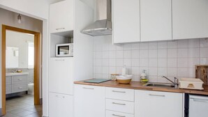 Ett modernt kök med vita skåp, en mikrovågsugn och en diskho.