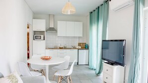 Ett kompakt bostadsutrymme med en matplats, ett litet kök och en TV.