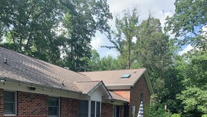 A brick house with a covered patio, a small garden, and a pathway leading to the entrance. - Charming 4-bedroom home with WiFi, AC ,  deck and firepit in delightful Montross (Montross)