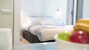 Een net opgemaakt bed met een deken in wit en grijs gestreept, een donkerbruin sprei en witte kussens.