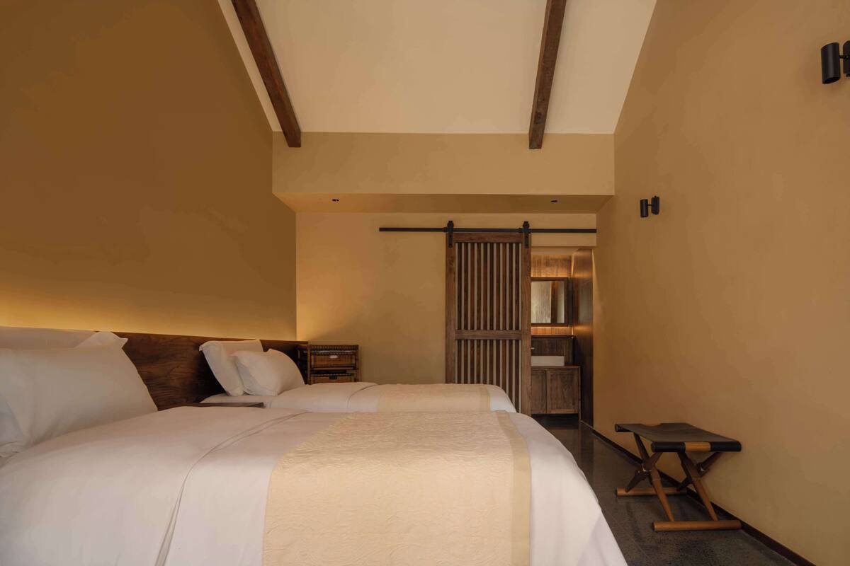 A bedroom with a large bed, a wooden headboard, a nightstand, and a small table.