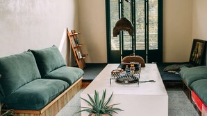 Una sala de estar con un sofá verde, una mesa de centro blanca y una estantería de madera.