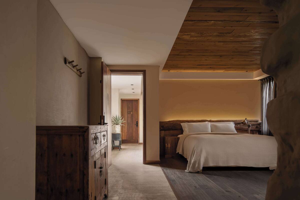 A bedroom with a wooden headboard, a bed with white linens, a nightstand, and a dresser.