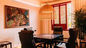 A dining area with a wooden table, leather chairs, a hanging woven light fixture, and a large colorful artwork on the wall. - YueLore Retreat (Chengdu)