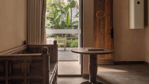 A room with a wooden bench, a round table, and a door leading to a balcony with plants. - YueLore Retreat (Chengdu)