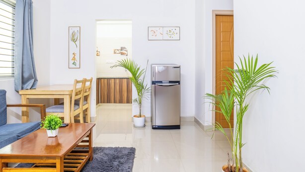 Una sala moderna con comedor, refrigerador y plantas en macetas.