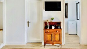 A room with a wooden cabinet, a flat-screen TV, and a white refrigerator.
