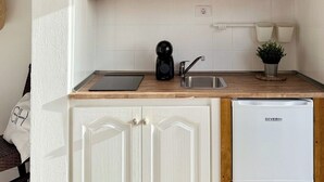 Una cocina con armarios de madera, una cafetera negra, un fregadero y un refrigerador blanco.