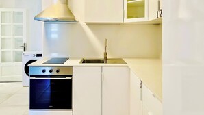 Una cocina compacta con horno integrado, placa de cocina y pileta de acero inoxidable.