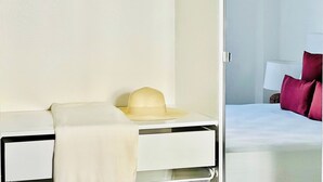 Une chambre d’hôtel avec un lit, une table de chevet sur laquelle se trouve un chapeau, et une lampe.