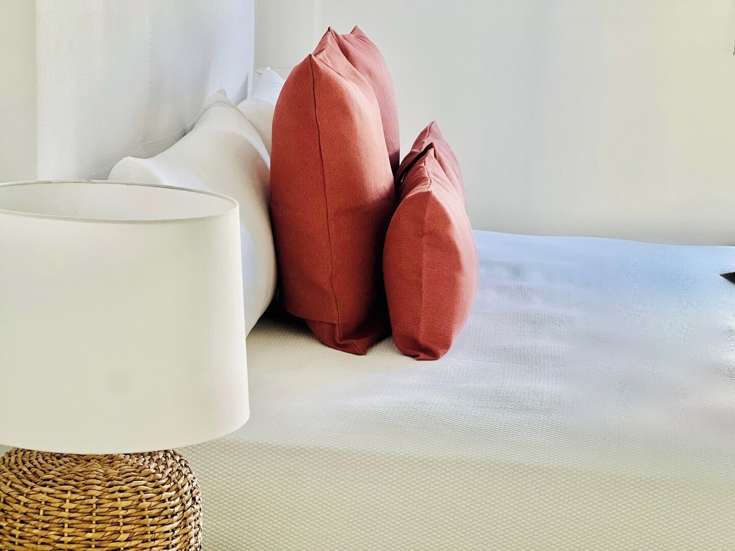 Un dormitorio ordenado con cama, almohadas y lámpara.