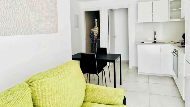 Un apartamento moderno con comedor, cocina y sala de estar con un sofá verde.