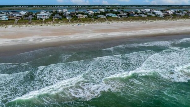 A coastal area with a beach and houses along the shore. - Everyone can relax at Salt Life (Topsail Beach)