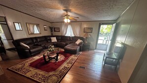 A living room with a sectional sofa, a glass coffee table, a red rug, and a ceiling fan.