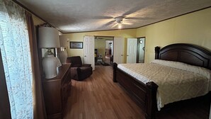 A bedroom with a bed, a desk, a chair, and a ceiling fan.