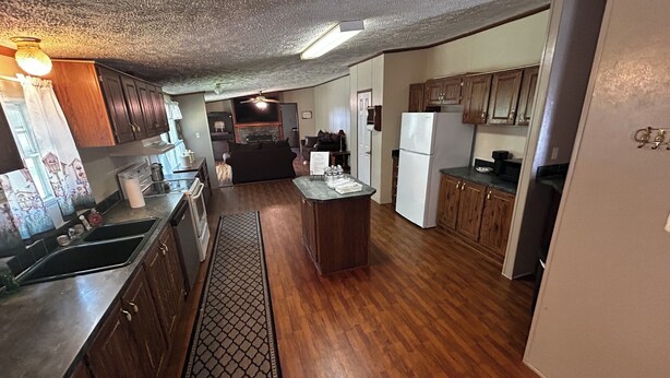 A compact kitchen with wooden cabinets, a central island, and a refrigerator.