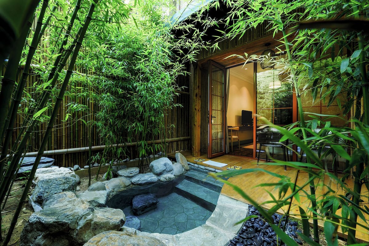 A traditional Japanese-style garden with a koi pond, bamboo, and a wooden deck.