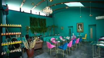Un restaurant à la décoration turquoise, agrémenté d’un lustre, de chaises colorées et d’un espace repas.