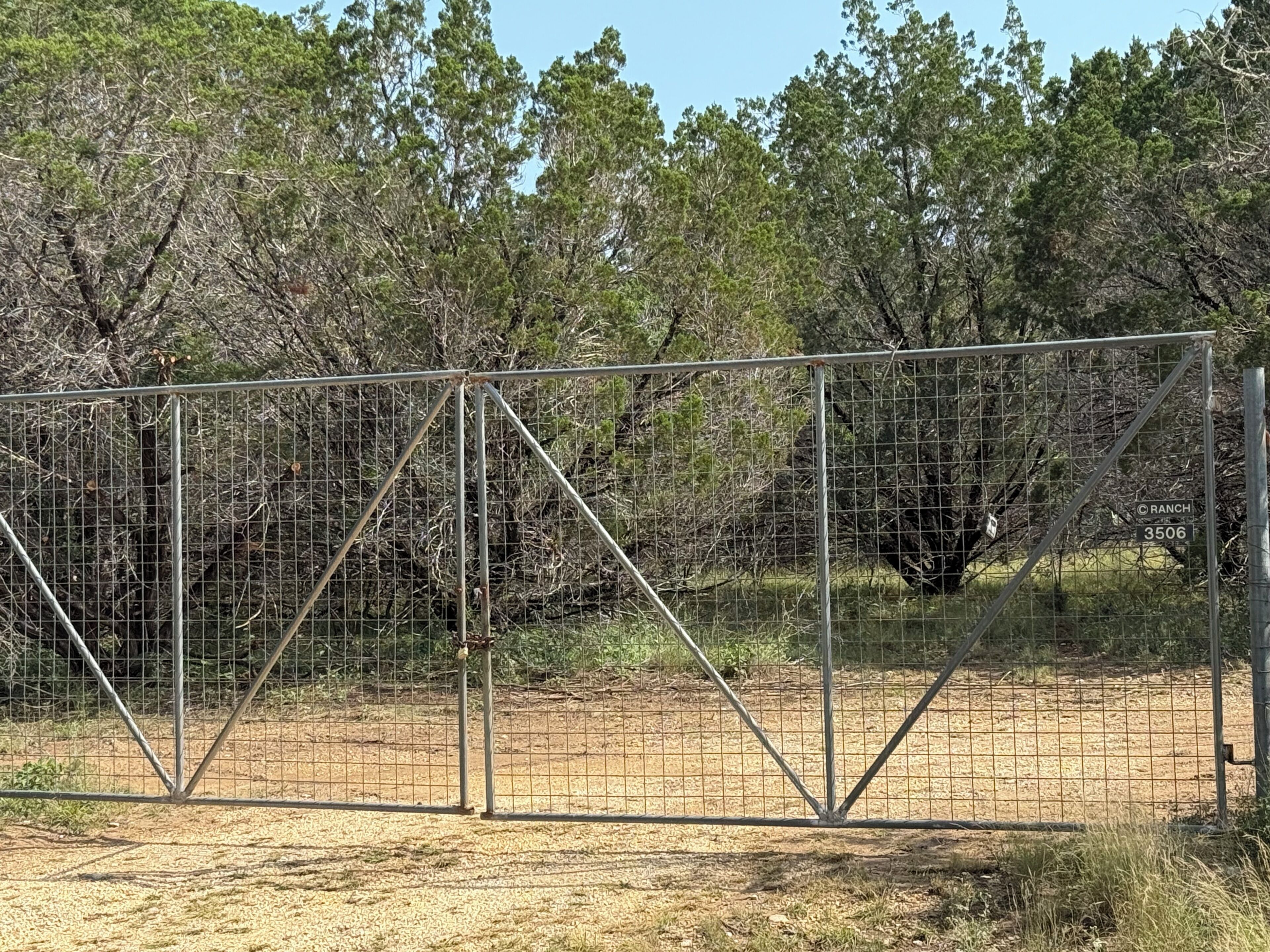 Un'area recintata con un cartello che riporta la scritta 'RANCH 3506' in un ambiente naturale.