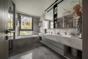 A modern bathroom with a large mirror, a bathtub, and a window providing natural light. - Wilderness Art Hotel (Chengdu)
