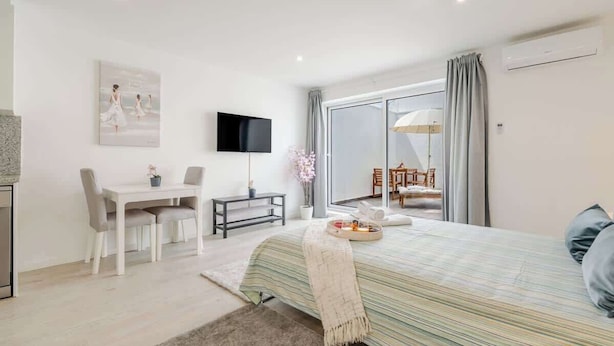 Quarto moderno com cama, escrivaninha e televisão.