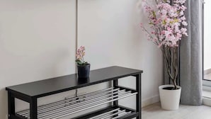 Uma sala de estar moderna com uma TV de tela plana na parede, uma mesinha lateral preta com uma orquídea em vaso e uma grande janela com cortinas cinzas.