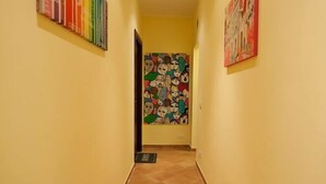 Ein Korridor mit gelben Wänden, einem gefliesten Boden und zwei Kunstwerken an den Wänden.