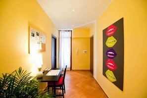 A narrow hallway with a dining table and chairs, a potted plant, and a wall with a colorful artwork. - Rome Services Porta Castello (Rome)