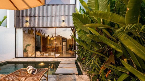 A modern house with a swimming pool, large windows, and tropical plants. - Charming 1-bedroom villa with swimming pool (Tibubeneng)