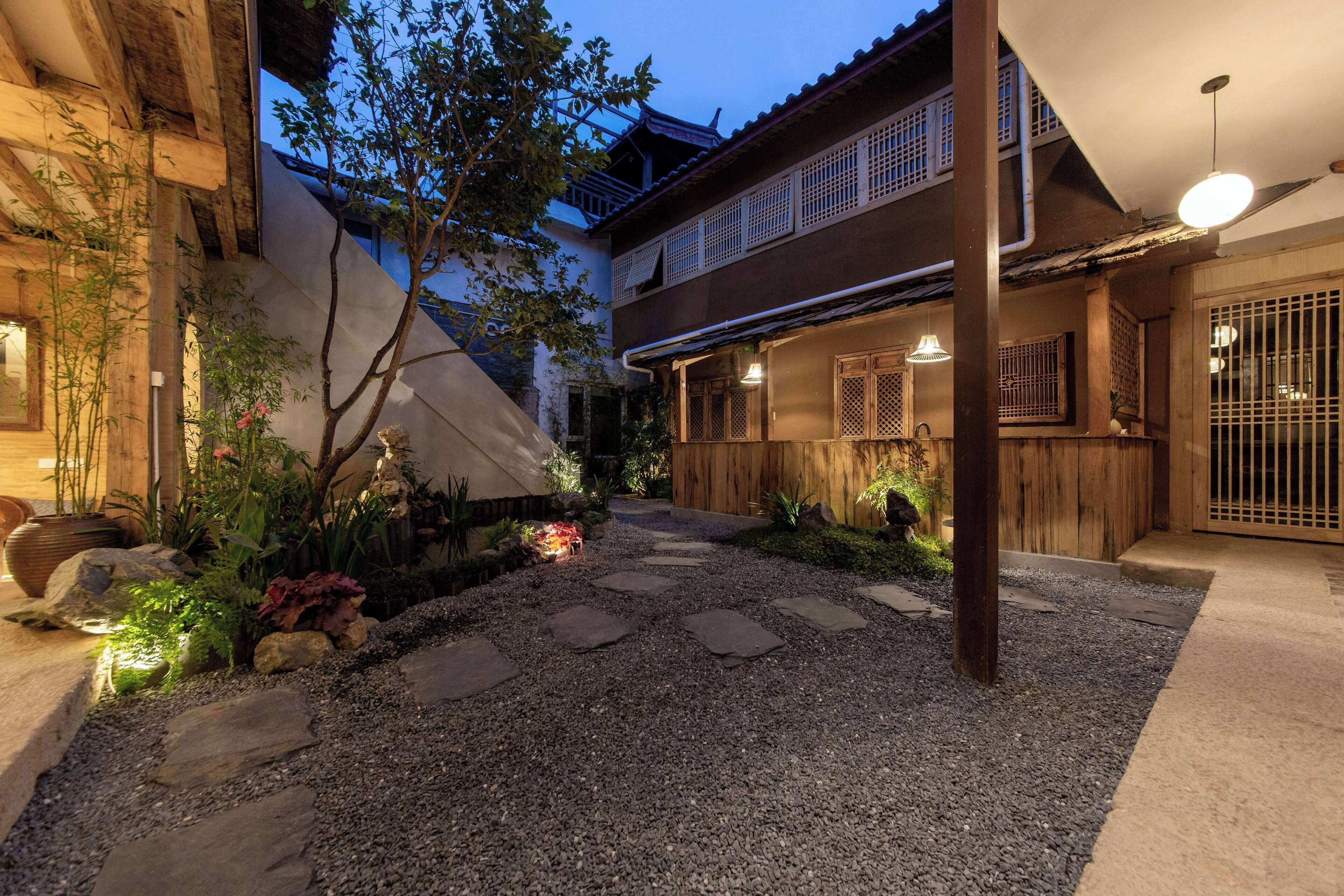 A courtyard with a gravel path, wooden steps, and potted plants.