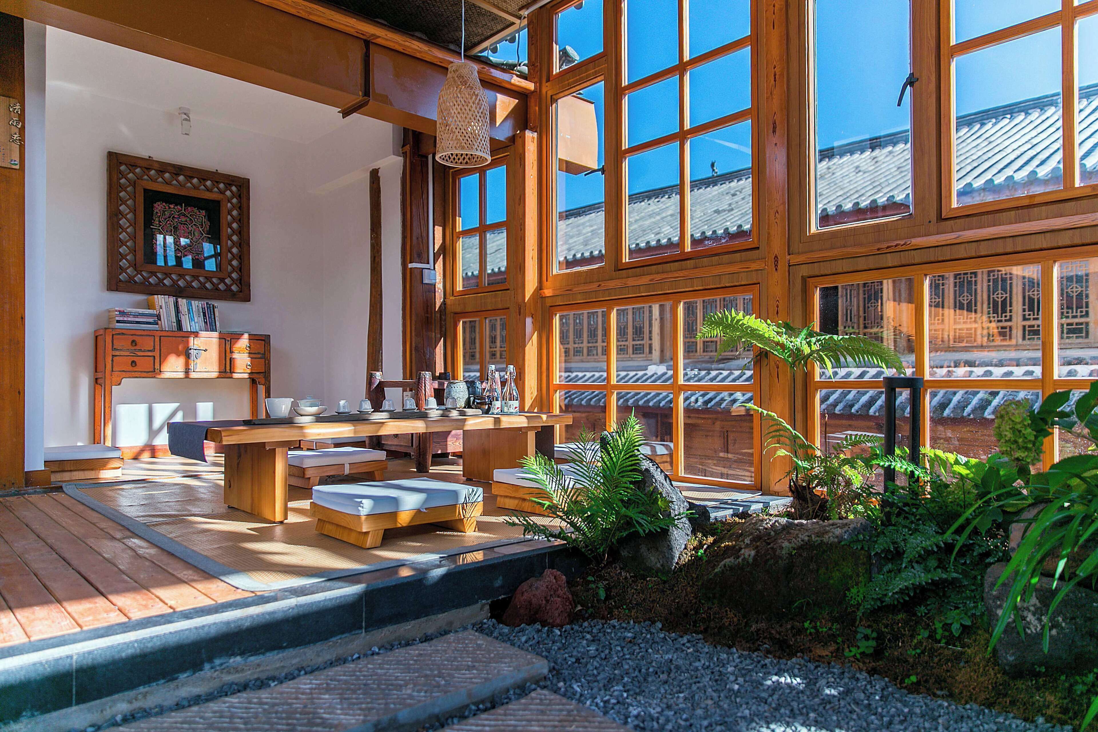 A traditional Japanese-style room with tatami flooring, wooden furniture, and large windows.