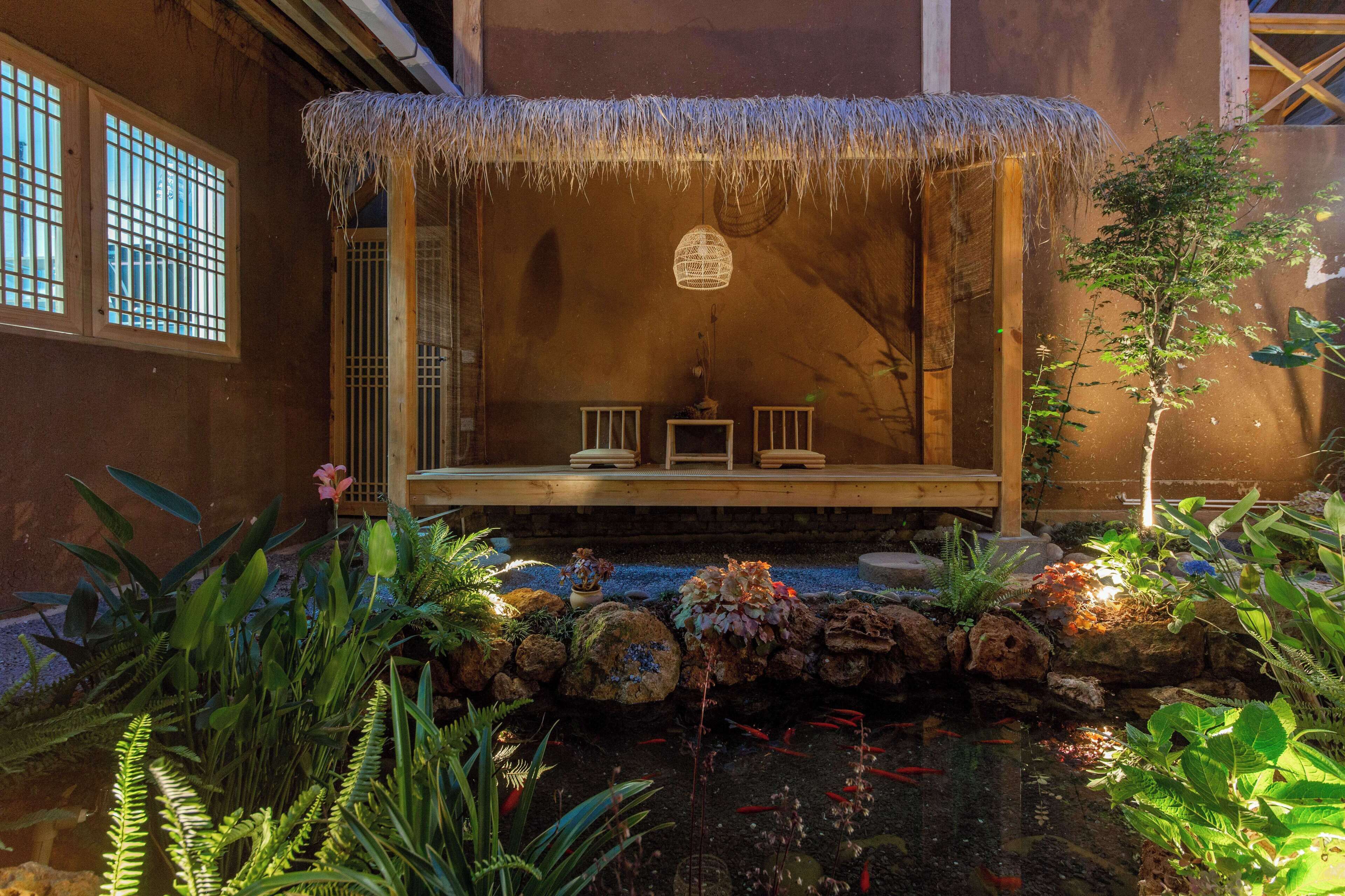 Una habitación tradicional japonesa con suelo de tatami, una mesa de madera baja y un tejado de paja sobre una pequeña zona de estar.